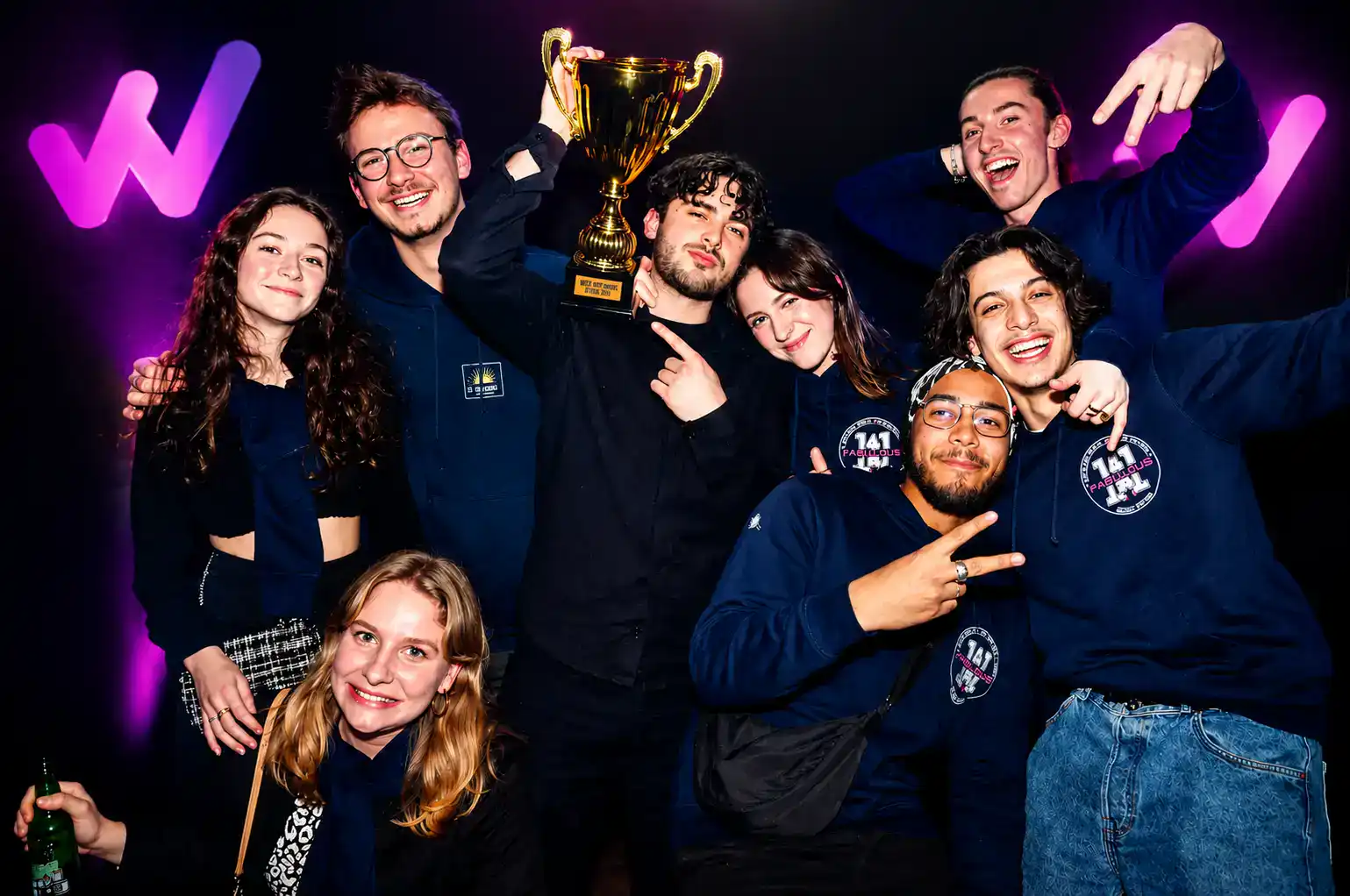Étudiants célébrant leur victoire lors des WECAY Night Awards avec un trophée devant le photocall WECAY